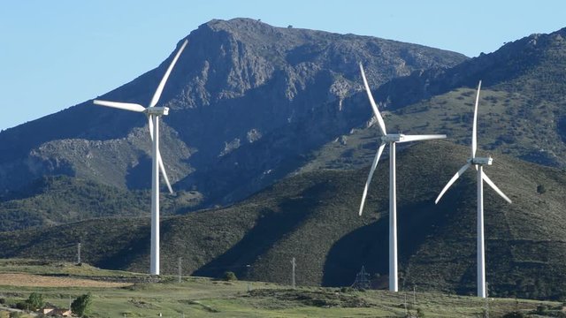 Wind turbines energy tower moving in the mountaints at sunny day