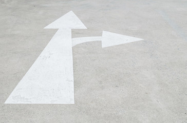 Closeup white painted arrow sign on cement street floor background , sign in go straight and turn right direction