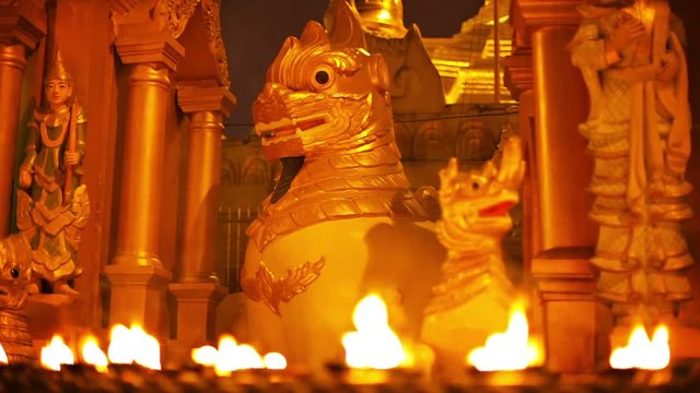Video 1080p - Statues of mythical monsters in a Buddhist temple at night. Ritual lighting with oil lamps. Myanmar, Yangon