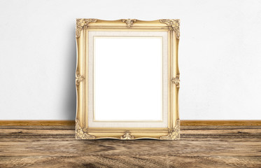 Blank golden vintage picture frame leaning at rustic wooden floo