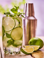 Alcohol lime cocktail. On wooden boards glass with alcohol cocktail and ice cubes. Drink two hundred twenty six cocktail mohito with cocktail shaker and mint leaf. Country life. Light background.