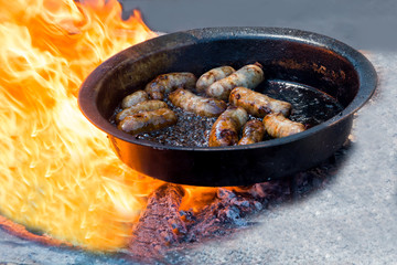 frying sausages in a frying pan on the fire