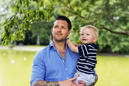 Father carrying toddler son in park