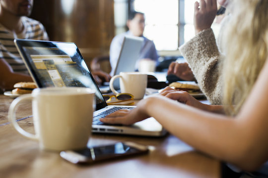 Cropped image of freelancers working on laptop at cafe