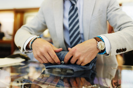 Midsection of salesman folding shirt on table in clothing store