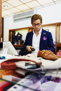 Salesman using bar code reader at checkout counter in clothing store