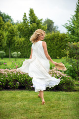 Fototapeta na wymiar Happy young blonde woman walking barefoot on the green grass
