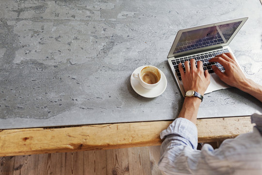 Man using laptop at stone table, close up of hands