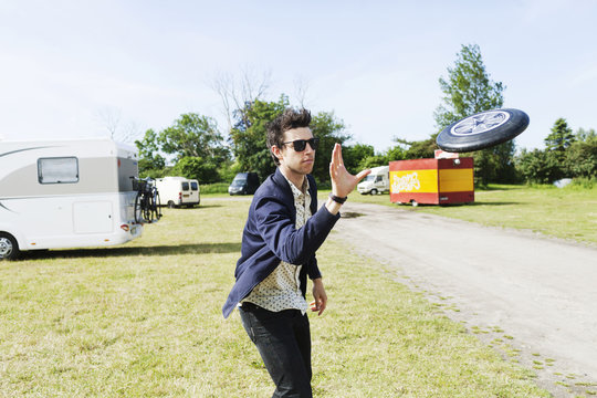 Man in sunglasses throwing plastic disc on grassy field