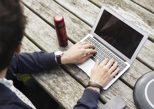 High angle view of man using laptop by plastic disc and bottle on table
