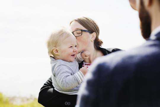 Mother Kissing Son By Father Against Clear Sky