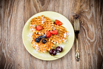 Waffles with berries on wooden background
