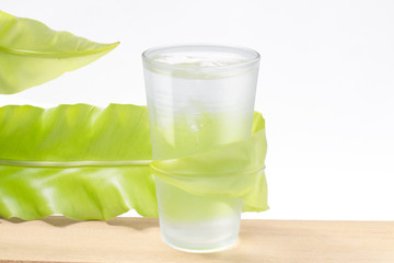 fresh water in glass with green leaf on white background