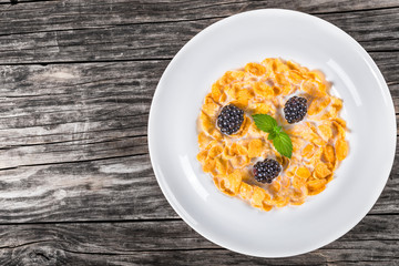 corn flakes with milk and dewberry in white dish