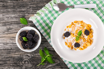 tasty corn flakes with milk and blackberry, top view