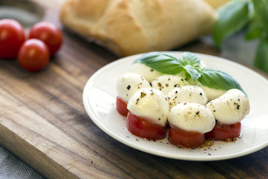 Mini Mozarella auf Tomatenscheiben mit buntem Pfeffer, Basilikum und Ciabattabrot