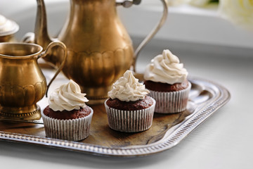 Tasty cupcakes with tea set on silver tray