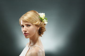 Portrait of young woman with elegant hairstyle on grey background