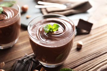 Chocolate mousse with mint in portion glasses on wooden background