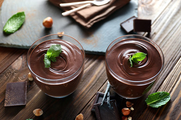 Chocolate mousse with mint in portion glasses on wooden background