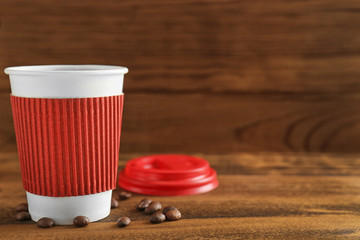 Paper cup of coffee on wooden background