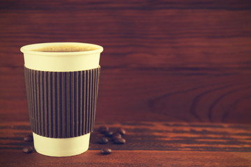 Paper cup of coffee on wooden background