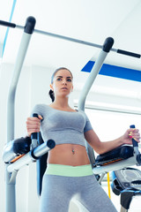 Beautiful and attractive young woman doing exercises at fitness gym.