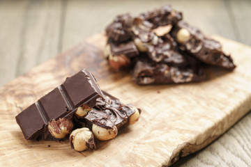 broken homemade bar of chocolate with cashew nuts on wood board