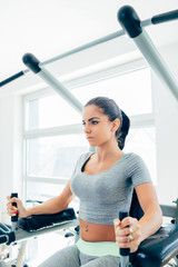 Beautiful and attractive young woman doing exercises at fitness gym.