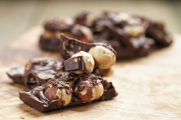 broken homemade bar of chocolate with cashew nuts on wood board