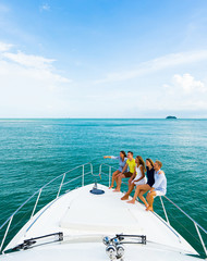 Friendship and happy young people sittingon the yacht deck looking and pointing away sailing the...