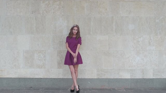 Young attractive woman posing near wall for fashion photographer