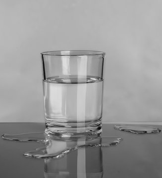 Glass and spilled water on grey background