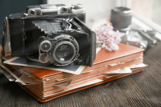 Vintage photos with camera and lilac on wooden background