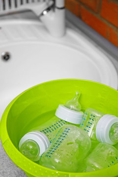 Sterilizing Baby Bottles In Plastic Green Basin