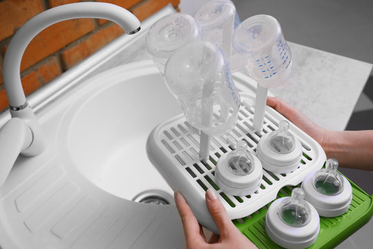 Woman Hands Holding Plastic Drying Rack With Baby Bottles