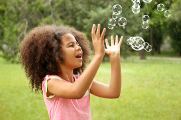 Afro-American little girl catching soap bubbles
