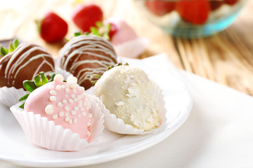 Strawberries covered with different chocolate on white plate