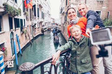 Fototapeta na wymiar Happy family take a self photo on the bridge over Venecian chann