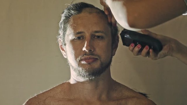Hairstyling process. Barber cutting hair of a young bearded man, time-lapse