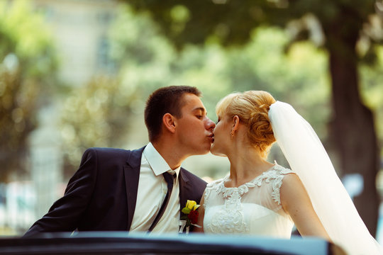 Fiance kisses bride tenderly sitting in an old car