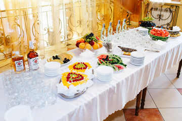Different kinds of fruits and drinks lie on the table in white p