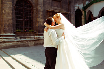 A wedding couple kiss in the lights of morning sun standing behi