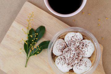 Banoffee cake in cup and black coffee, top view on wooden plate.