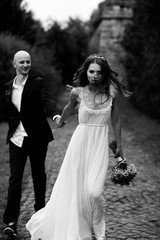 Fototapeta na wymiar Thin bride looks gorgeous walking with groom along the path