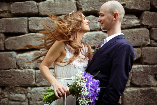 Bride smiles looking at a groom while wind blows her hair