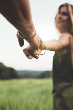 Man holding hand of his girlfriend in grass field