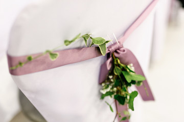 White chair decorated with violet ribbon and greenery over it