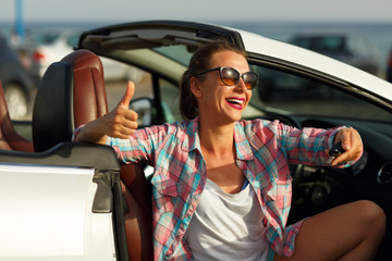 Young woman sitting in a convertible car with the keys in hand
