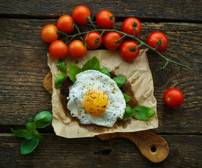 Scrambled eggs on toasted bread with basil, spices and cherry to